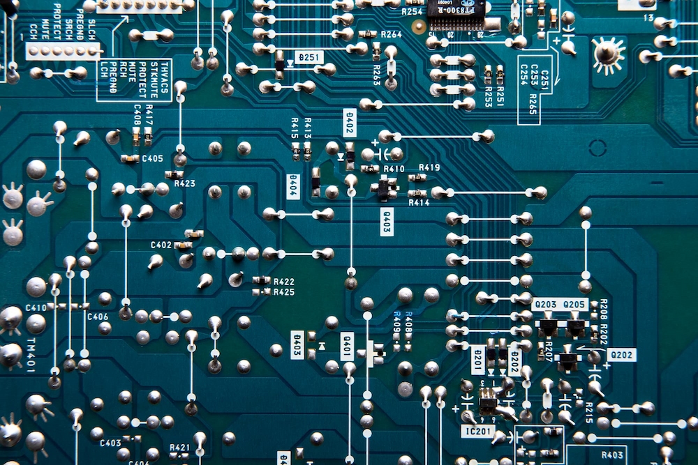 Spodnia strona płytki PCB z połączeniami lutowniczymi THT – widoczne spoiny po lutowaniu przewlekanym oraz komponenty przez-otworowe: kondensatory elektrolityczne, złącza i tranzystor mocy z radiatorem