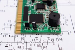 Płytka PCB z układami scalonymi SMD leżąca na schemacie elektrycznym – projektowanie układów elektronicznych na zamówienie RGBpro